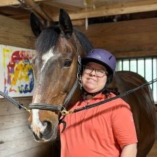 Brittany with a brown horse in his stall at The Bridge Center
