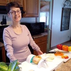 Lisa smiles while showing off her adaptive cooking tools