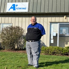 Tim Vaughn - an HVRP participant, posing and smiling in front of his new workplace at A+ Towing.