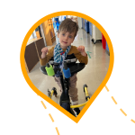 Boy using a gait trainer smiles at the camera