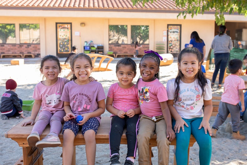 Five children sitting on a bench and smiling