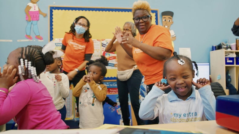 Katelyn playing with her friends and teachers in the classroom