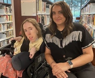 Erin (left) and Lily (right) smiling in front of books in a library