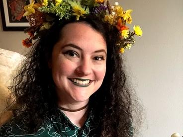 Anna Goldberg with flowers on her head playing a colorful ukelele