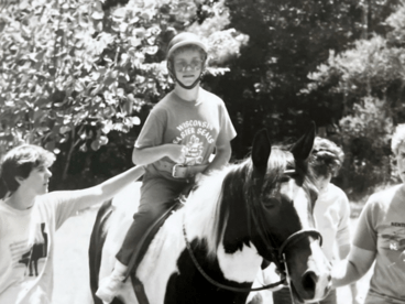 Rhonda rides a horse a camp