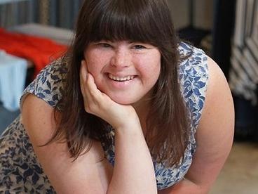 Collette Divitto smiling delightfully, leaning on a table with a tray full of cookies and a cup of milk