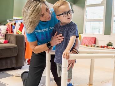 Luke, a young boy, works with an Easterseals therapist using supports to walk