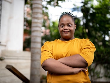 Portrait of a young woman with Down syndrome, arms crossed, determined smile