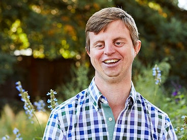 Dr. Hoby Wedler smiling, in front of tall greenery