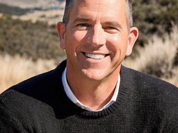 Steve Guthrie smiling in front of a hilly landscape