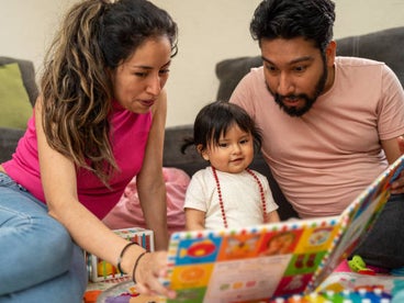 Parents reading a book with their toddler.