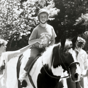 Rhonda rides a horse a camp