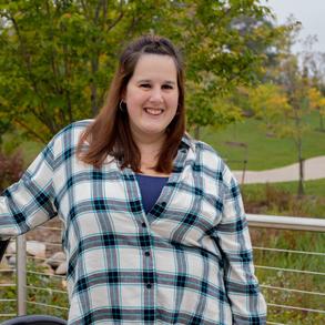 Sarah, relaxed and smiling, against a fence