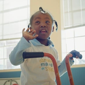 Katelyn waves as she sits on a bike