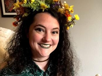 Anna Goldberg with flowers on her head playing a colorful ukelele