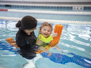 Nolan, a young child, works with an Easterseals therapist swimming in a pool