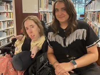 Erin (left) and Lily (right) smiling in front of books in a library