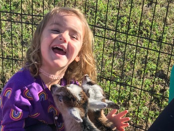 young girl with disability plays with baby goats