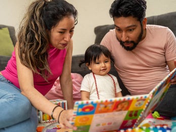 Parents reading a book with their toddler.