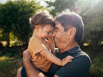 Playful grandfather spending time with his grandson in park on sunny day