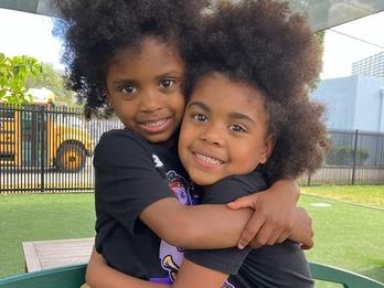 Two young boys, twins, hug at a playground
