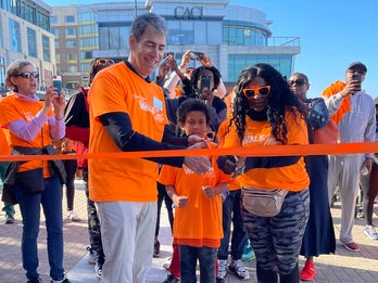 Walk With Me fundraiser at which 2 adults and a child cut the race ribbon