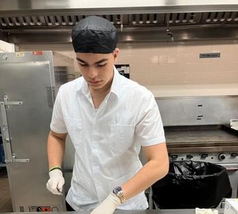 Sebastian slices meat in an industrial kitchen