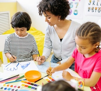 A woman in a classroom teaching two young children