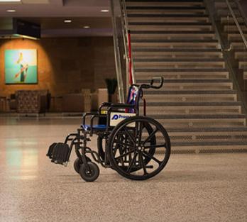 An airport wheelchair by a set of stairs at the airport