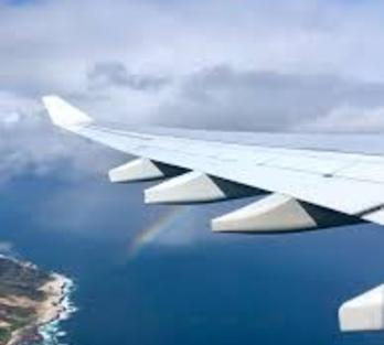 The wing of an airplane over a body of water
