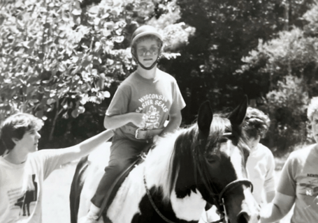 Rhonda rides a horse a camp