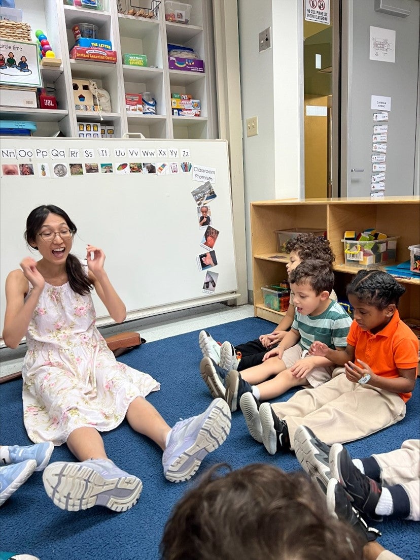 Ms. Saori on floor with kids giving music lesson