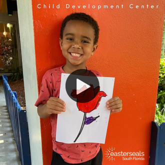 Jayden smiling holding up drawing