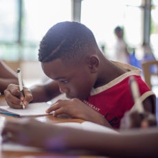 boy writing on printer paper 