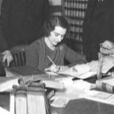 Black and white image of Dorothy Kellogg writing at a desk.